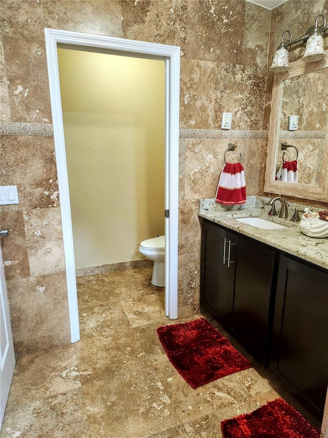 bathroom featuring vanity, toilet, and tile walls