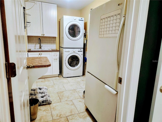 laundry room featuring sink, light tile patterned floors, cabinets, and stacked washer / drying machine