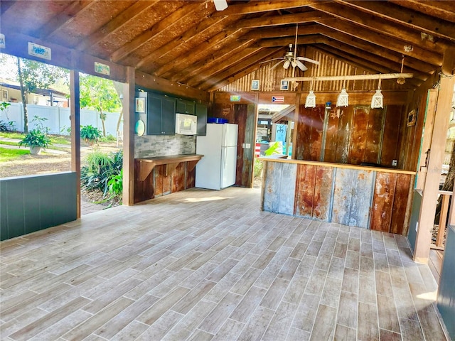 kitchen featuring ceiling fan, wood walls, wood-type flooring, vaulted ceiling, and white appliances