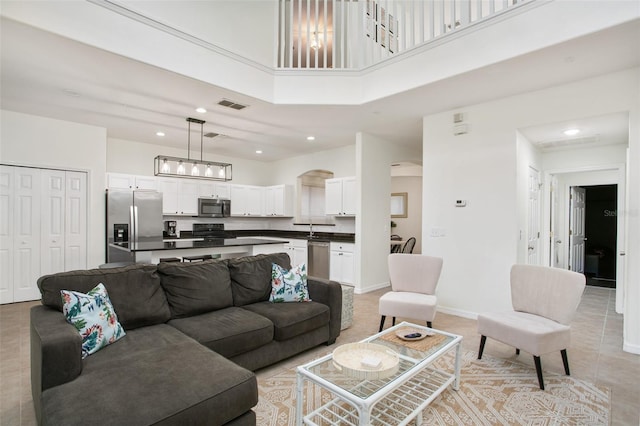 living room featuring light tile patterned floors, sink, and a high ceiling