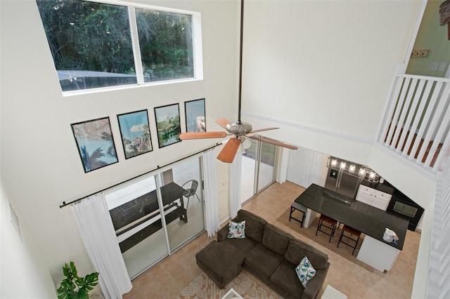 living room featuring ceiling fan, light carpet, and a high ceiling