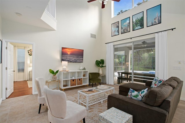 living room with light wood-type flooring, a towering ceiling, and ceiling fan