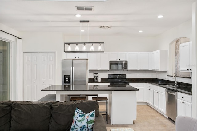 kitchen with sink, hanging light fixtures, stainless steel appliances, a kitchen bar, and a kitchen island