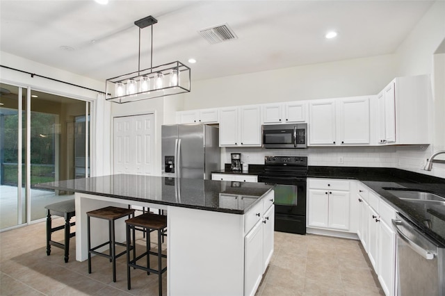 kitchen featuring hanging light fixtures, sink, appliances with stainless steel finishes, a kitchen island, and white cabinetry