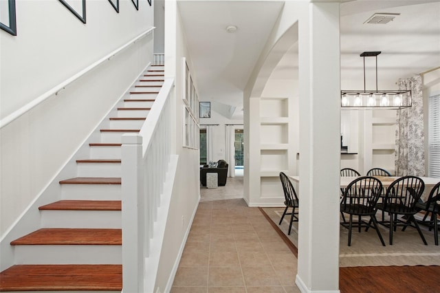 staircase with hardwood / wood-style floors and a notable chandelier