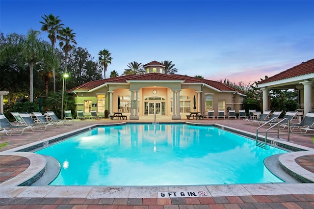 pool at dusk with a patio area