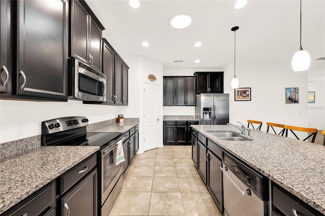 kitchen featuring pendant lighting, light stone counters, sink, and appliances with stainless steel finishes