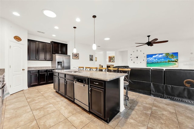 kitchen featuring sink, stainless steel appliances, a kitchen breakfast bar, pendant lighting, and a center island with sink