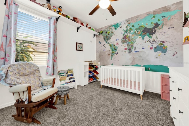 carpeted bedroom featuring ceiling fan and a nursery area