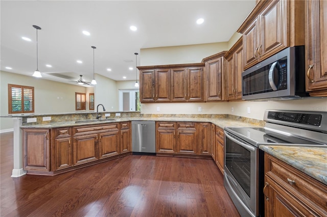 kitchen featuring sink, hanging light fixtures, dark hardwood / wood-style flooring, kitchen peninsula, and appliances with stainless steel finishes