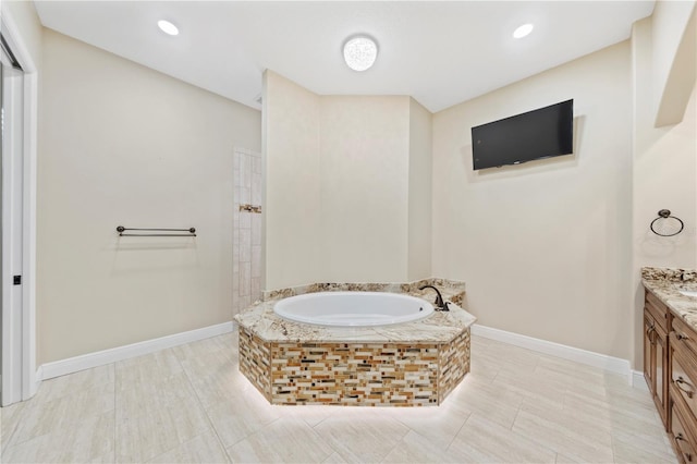 bathroom with vanity and tiled bath