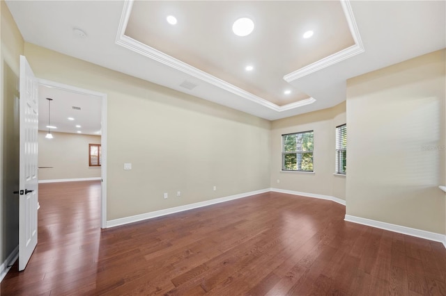 unfurnished room featuring dark hardwood / wood-style floors, a raised ceiling, and ornamental molding