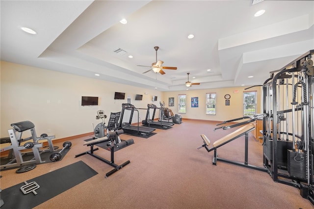 gym with a raised ceiling and ceiling fan