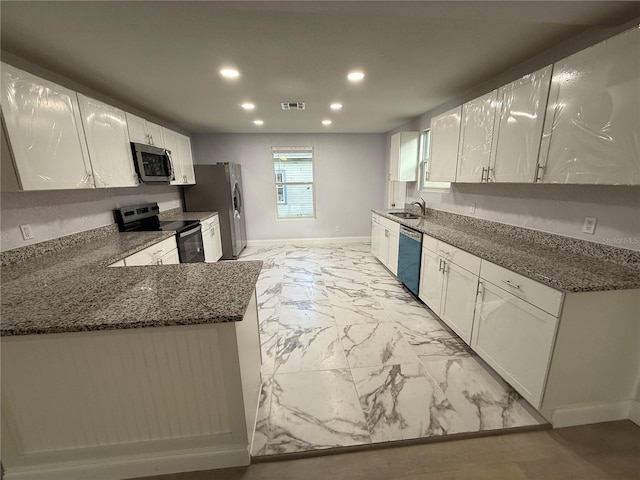 kitchen with dark stone counters, sink, white cabinets, and stainless steel appliances