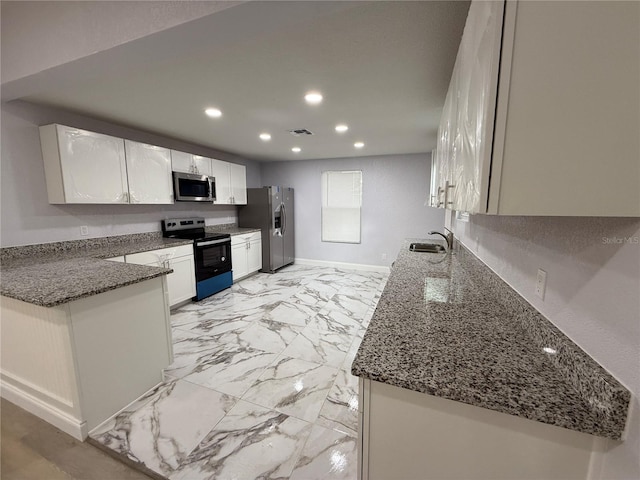 kitchen with white cabinets, sink, stainless steel appliances, and dark stone countertops