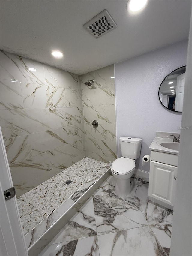 bathroom featuring toilet, vanity, and tiled shower