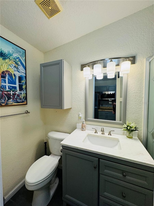 bathroom with vanity, a textured ceiling, and toilet