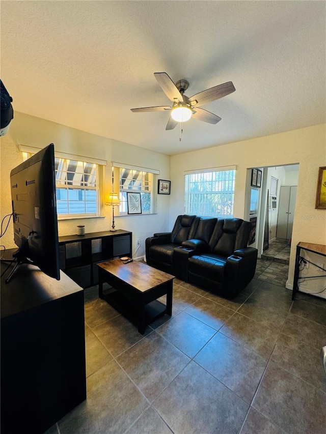 living room with tile patterned floors, ceiling fan, and a textured ceiling