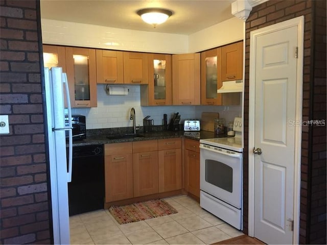 kitchen featuring dark stone counters, brick wall, white appliances, sink, and light tile patterned floors