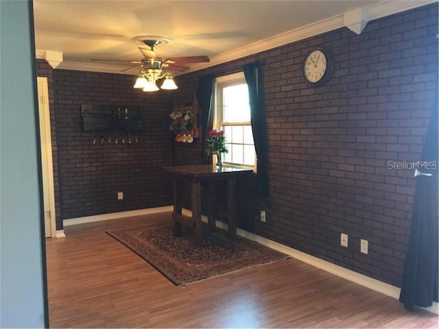 office area with ceiling fan, wood-type flooring, and brick wall