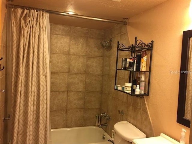 bathroom with shower / bath combo with shower curtain, a textured ceiling, and toilet