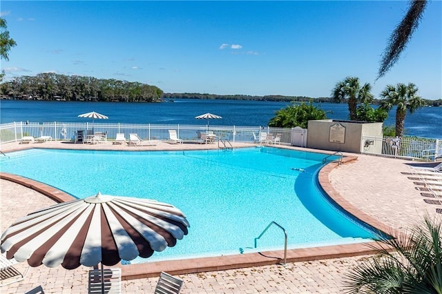 view of swimming pool with a patio area and a water view