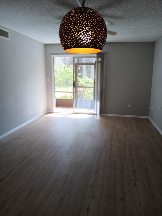 spare room with baseboards, a textured ceiling, visible vents, and wood finished floors