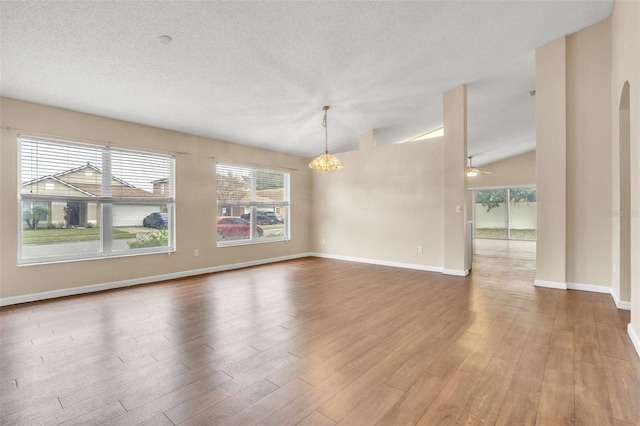 spare room with hardwood / wood-style flooring, vaulted ceiling, a healthy amount of sunlight, and a textured ceiling