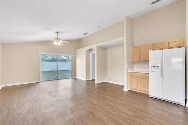 kitchen featuring vaulted ceiling, dark hardwood / wood-style flooring, white fridge with ice dispenser, ceiling fan, and light brown cabinets