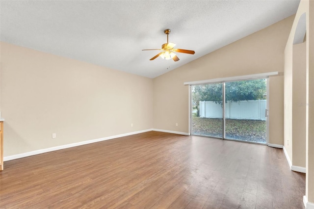 empty room featuring hardwood / wood-style flooring, vaulted ceiling, a textured ceiling, and ceiling fan