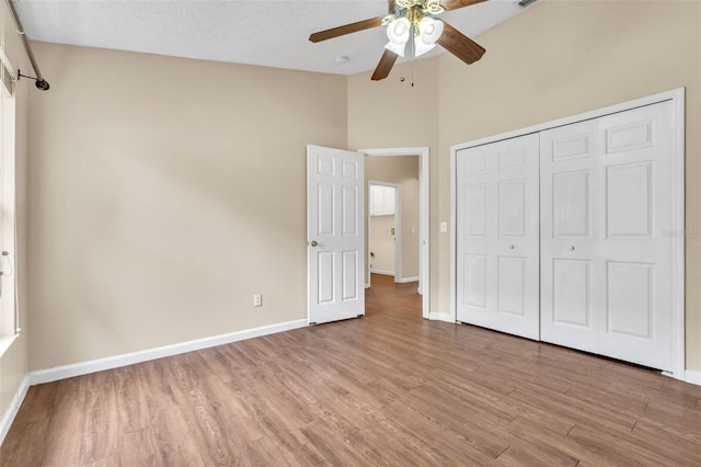 unfurnished bedroom with vaulted ceiling, a closet, ceiling fan, and light wood-type flooring