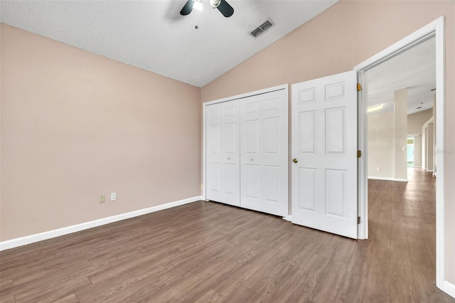 unfurnished bedroom with hardwood / wood-style flooring, ceiling fan, vaulted ceiling, and a closet