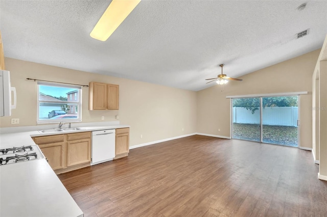 kitchen with lofted ceiling, sink, white appliances, and light brown cabinets