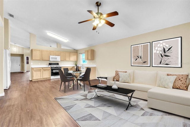 living room with vaulted ceiling, light hardwood / wood-style floors, and ceiling fan