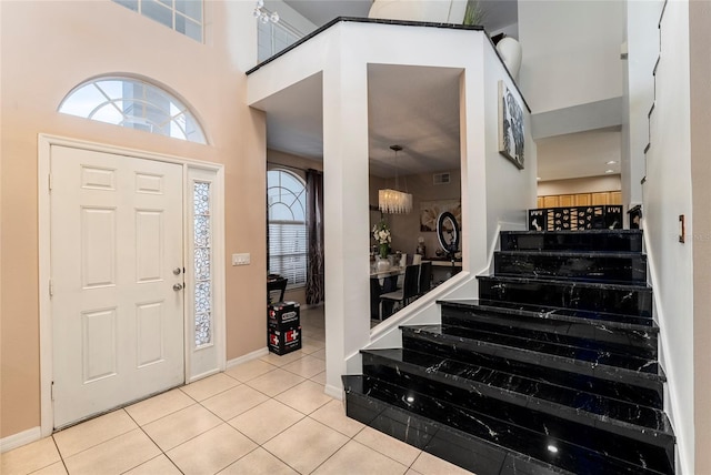 tiled foyer entrance with a towering ceiling and an inviting chandelier