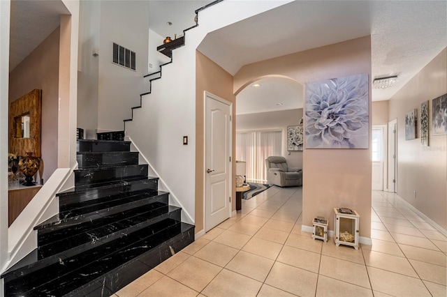 staircase with tile patterned flooring, a healthy amount of sunlight, and a textured ceiling