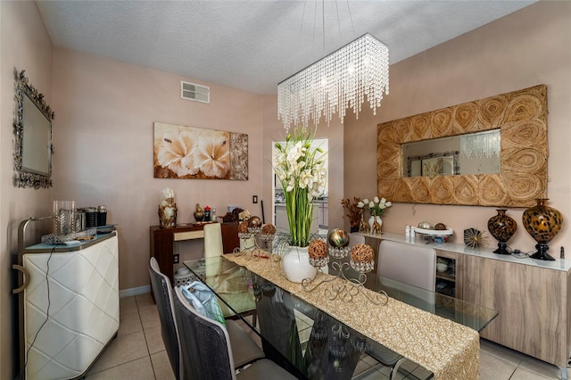 tiled dining space featuring a textured ceiling and an inviting chandelier