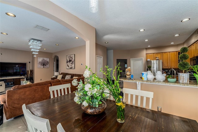 dining room with a chandelier, a textured ceiling, and light wood-type flooring