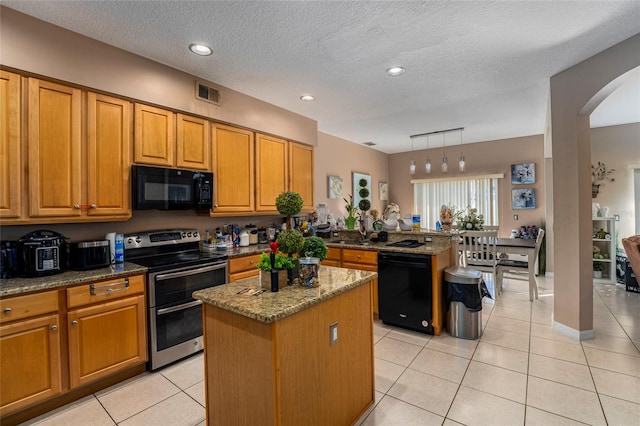 kitchen featuring light stone countertops, a textured ceiling, black appliances, a center island, and hanging light fixtures