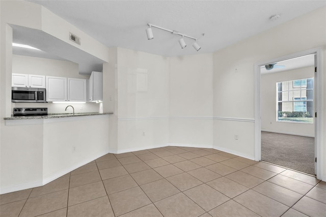 unfurnished room with sink, rail lighting, and light tile patterned flooring