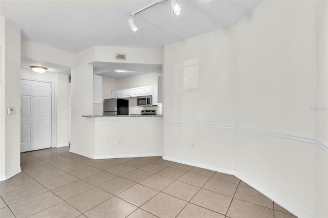 kitchen with light stone counters, stainless steel appliances, light tile patterned floors, and white cabinets