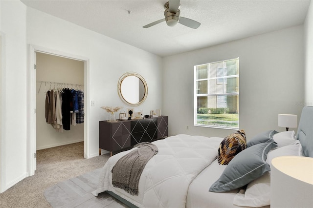 bedroom featuring ceiling fan, a spacious closet, light colored carpet, and a closet