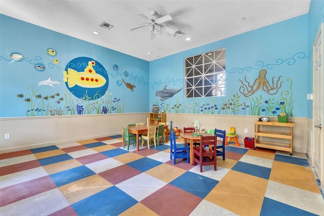 playroom with ceiling fan and a textured ceiling