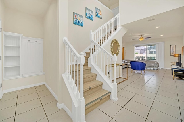 stairway with a high ceiling, tile patterned floors, and ceiling fan