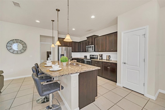 kitchen with sink, decorative light fixtures, a breakfast bar area, a center island with sink, and appliances with stainless steel finishes