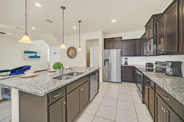 2468 Dubai St, Kissimmee, FL 34747 - kitchen featuring appliances with stainless steel finishes, dark brown cabinets, light tile patterned floors, light stone countertops, and recessed lighting