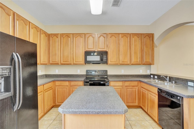 kitchen featuring black appliances, a kitchen island, light tile patterned floors, and sink