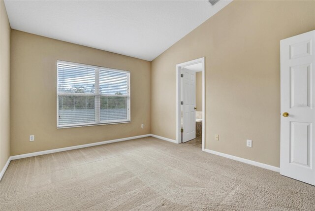 spare room with light colored carpet and lofted ceiling