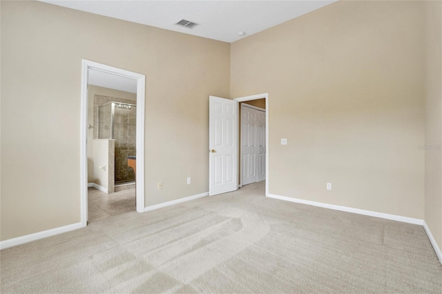 unfurnished bedroom with ensuite bath and light colored carpet