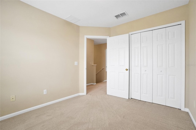 unfurnished bedroom featuring light colored carpet and a closet